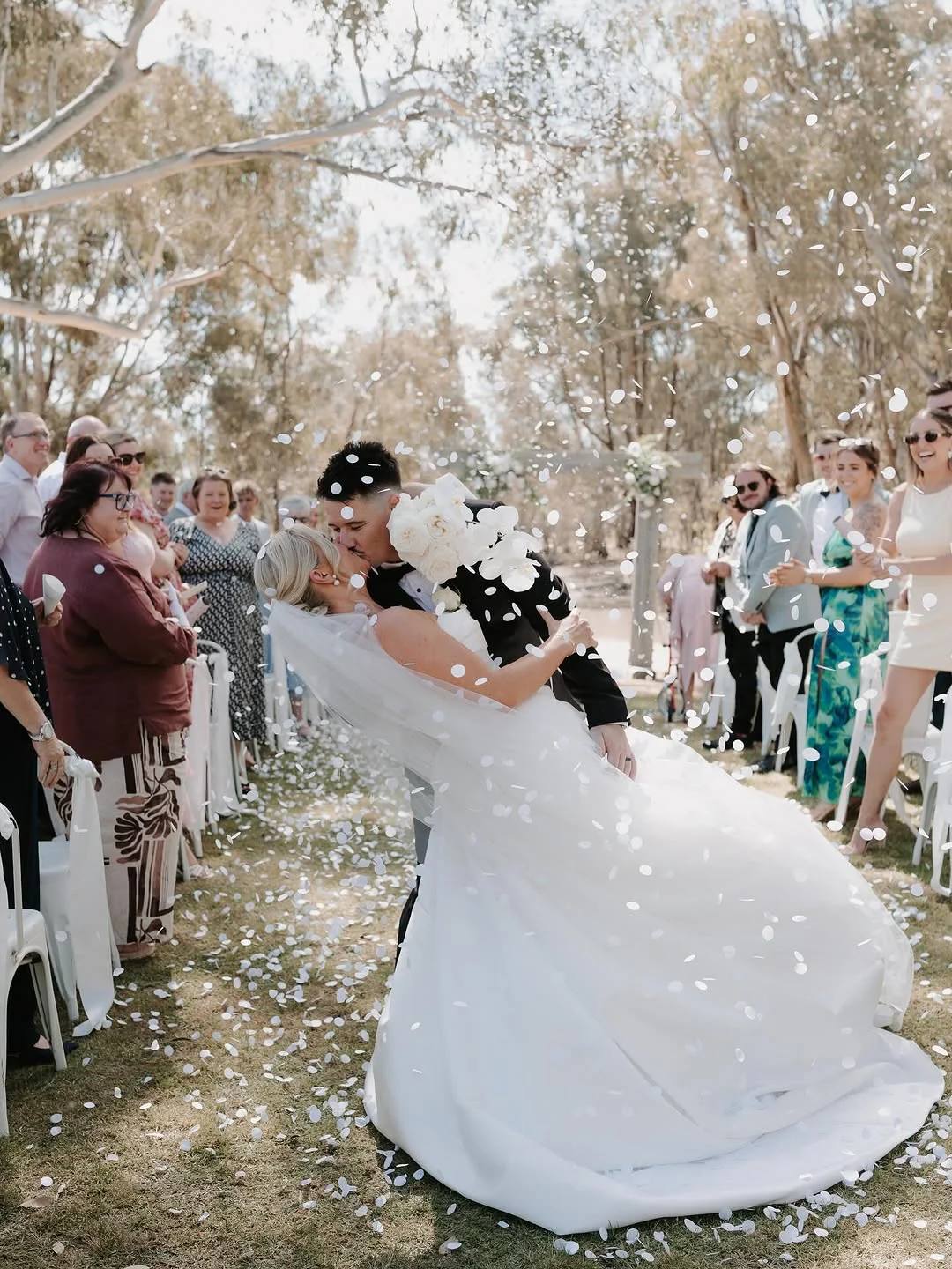 Friends and family lining the aisle and throwing confetti around the newly married couple